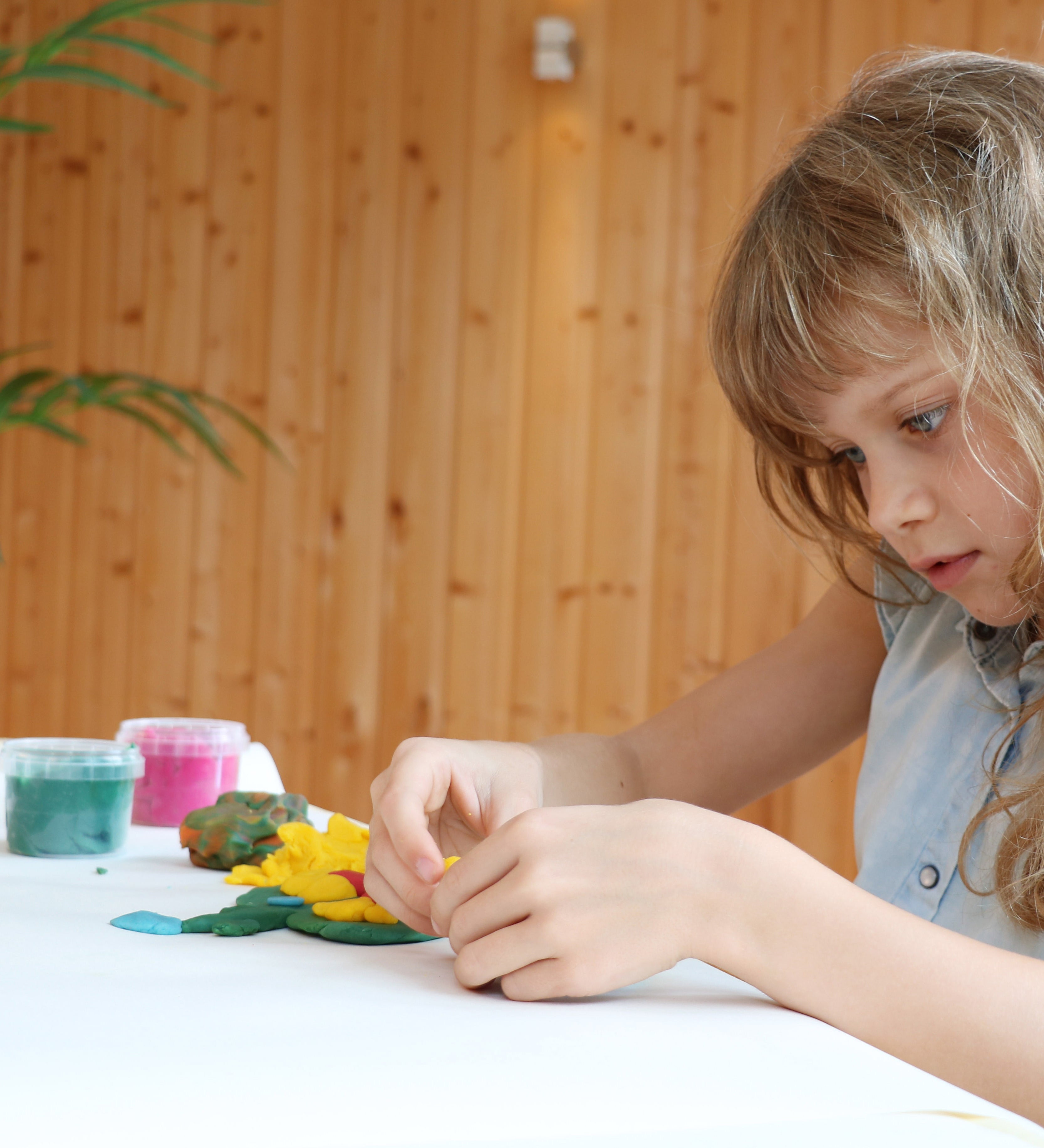 A child sitting beside a table playing with the Neogrun organic play dough on a white table cloth