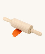 Neogrun wooden rolling pin on top of the orange organic play dough. Features handles on each side for easy handling