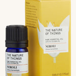 Neroli pure essential oil in a blue glass bottle in front of a decorative yellow cardboard box.