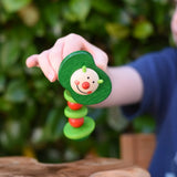 Nic apple worm baby wooden grasping toy in a child's hand. Smiling worm on a flexible rope lined with chunky red and green beads. 