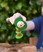 Nic apple worm baby wooden grasping toy in a child's hand. Smiling worm on a flexible rope lined with chunky red and green beads. 