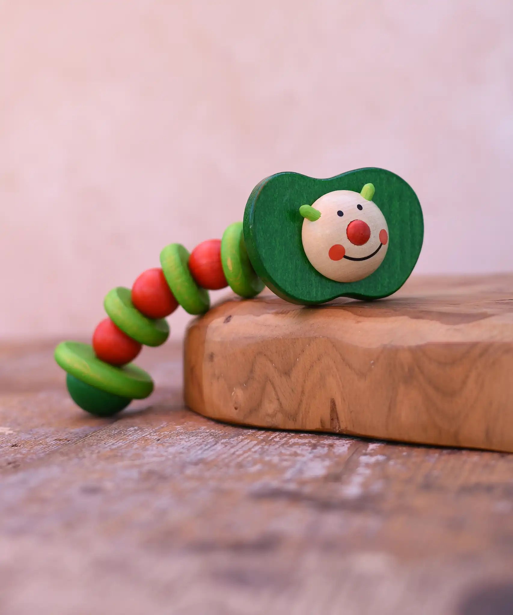 Nic apple worm baby wooden grasping toy. Smiling worm on a flexible rope lined with chunky red and green beads.