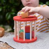 Child playing with the Nic BIO red rolling shape sorter wooden toy with 6 wooden blocks.