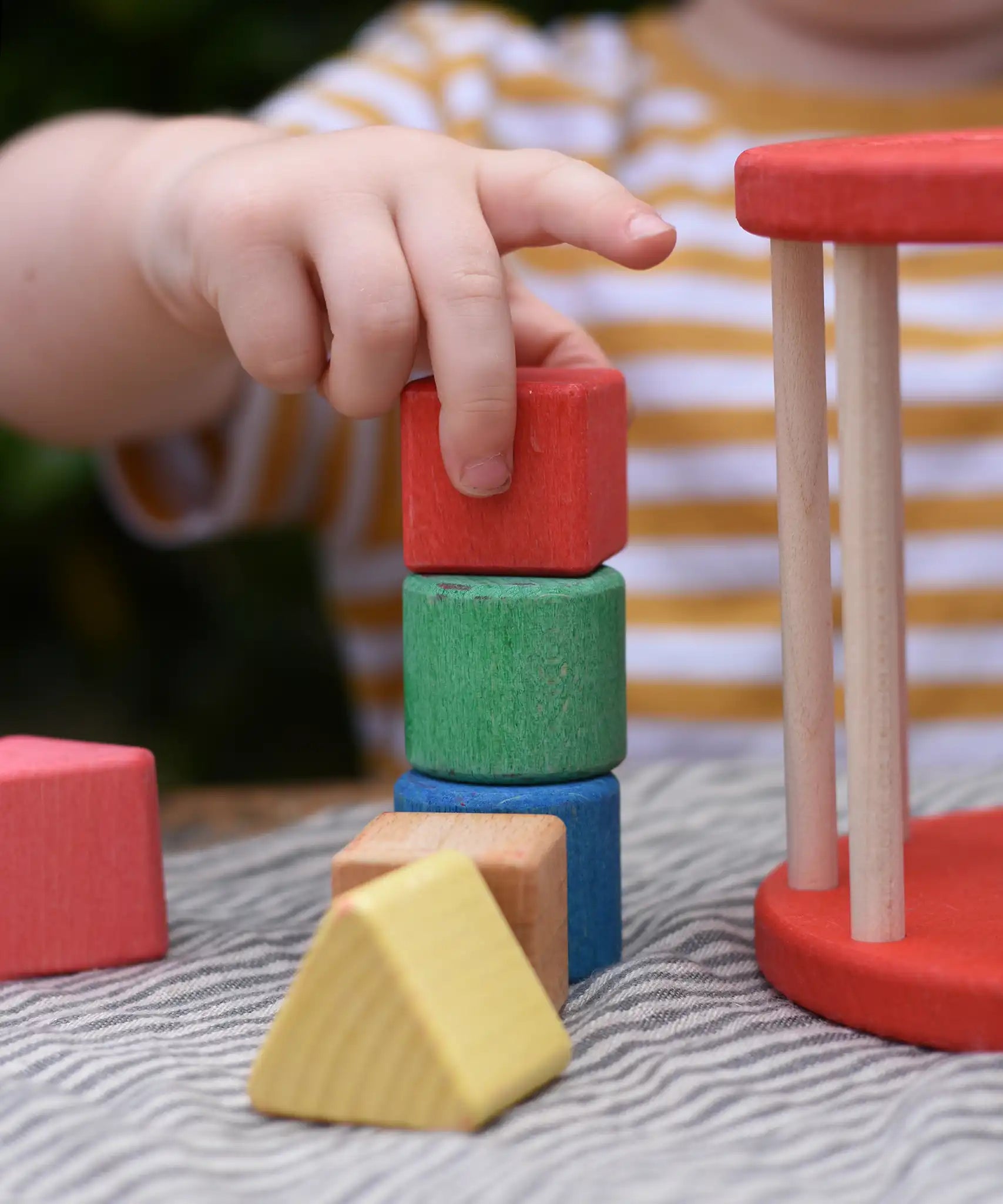 Child stacking blocks from the Nic BIO red rolling shape sorter wooden toy.