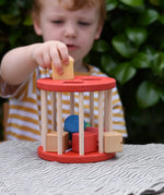 Child playing with the Nic BIO red rolling shape sorter wooden toy with 6 wooden blocks.