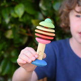 Child holding the Nic Toys bio wooden rattling tree baby toy. Coloured disks for making a noise and a wooden handle for grip.