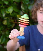 Child holding the Nic Toys bio wooden rattling tree baby toy. Coloured disks for making a noise and a wooden handle for grip.