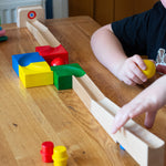 The Nic Cubio wooden starter ball track set shown set up on a wooden table with the outlet piece with ringing bell added to the end.
