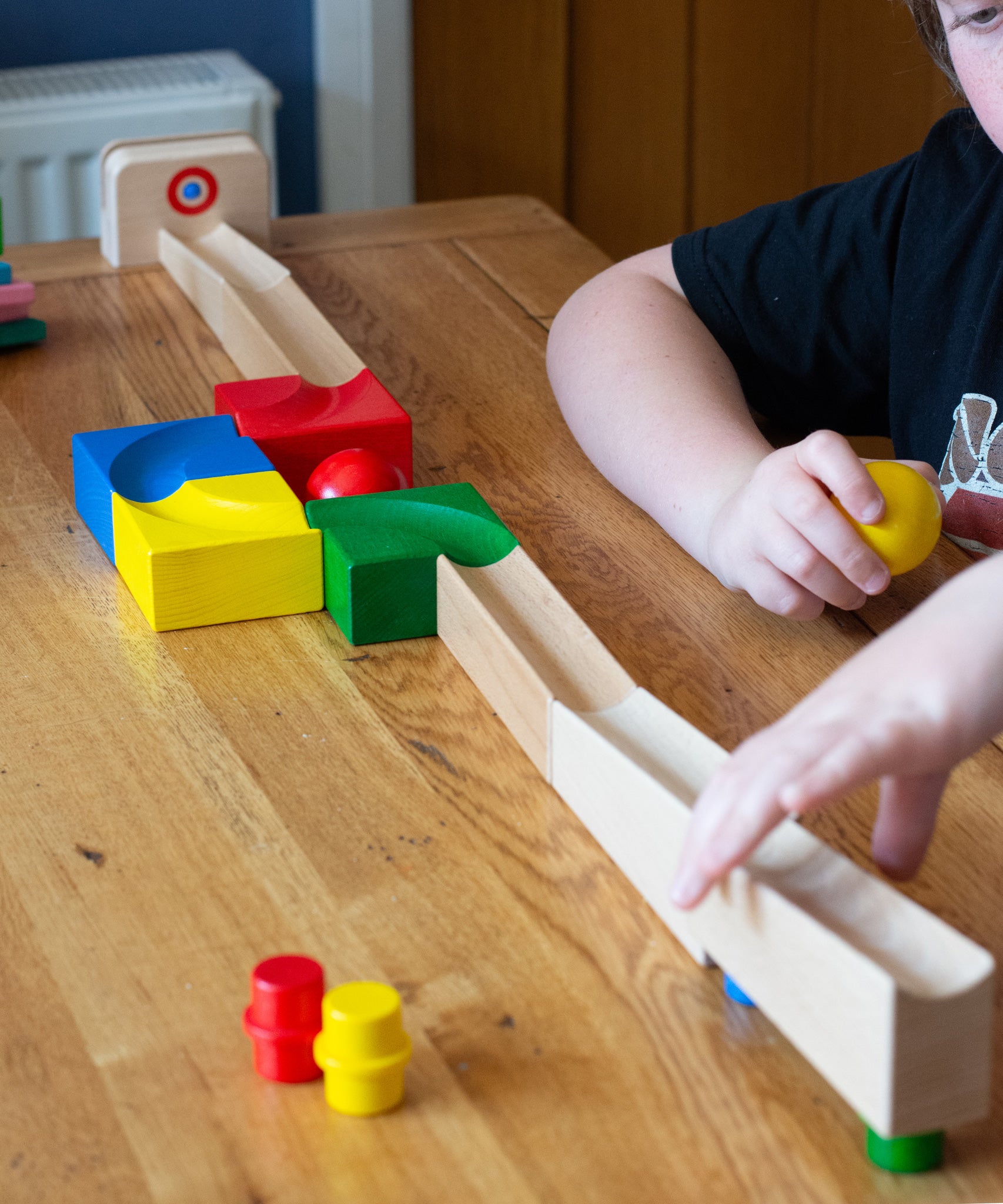 The Nic Cubio wooden starter ball track set shown set up on a wooden table with the outlet piece with ringing bell added to the end.