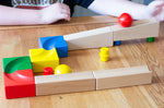 The Nic Cubio Wooden Marble Run Starter Set shown set up on a wooden table. A red coloured ball can be seen in motion at the start of the track.