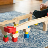 Nic Cubio wooden Ball Track Extension Set shown set up, a child has just placed a red ball on the track. Wooden balls are available to purchase separately. 
