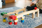 Nic Cubio wooden Ball Track Extension Set shown set up, a child has just placed a red ball on the track. Wooden balls are available to purchase separately. 