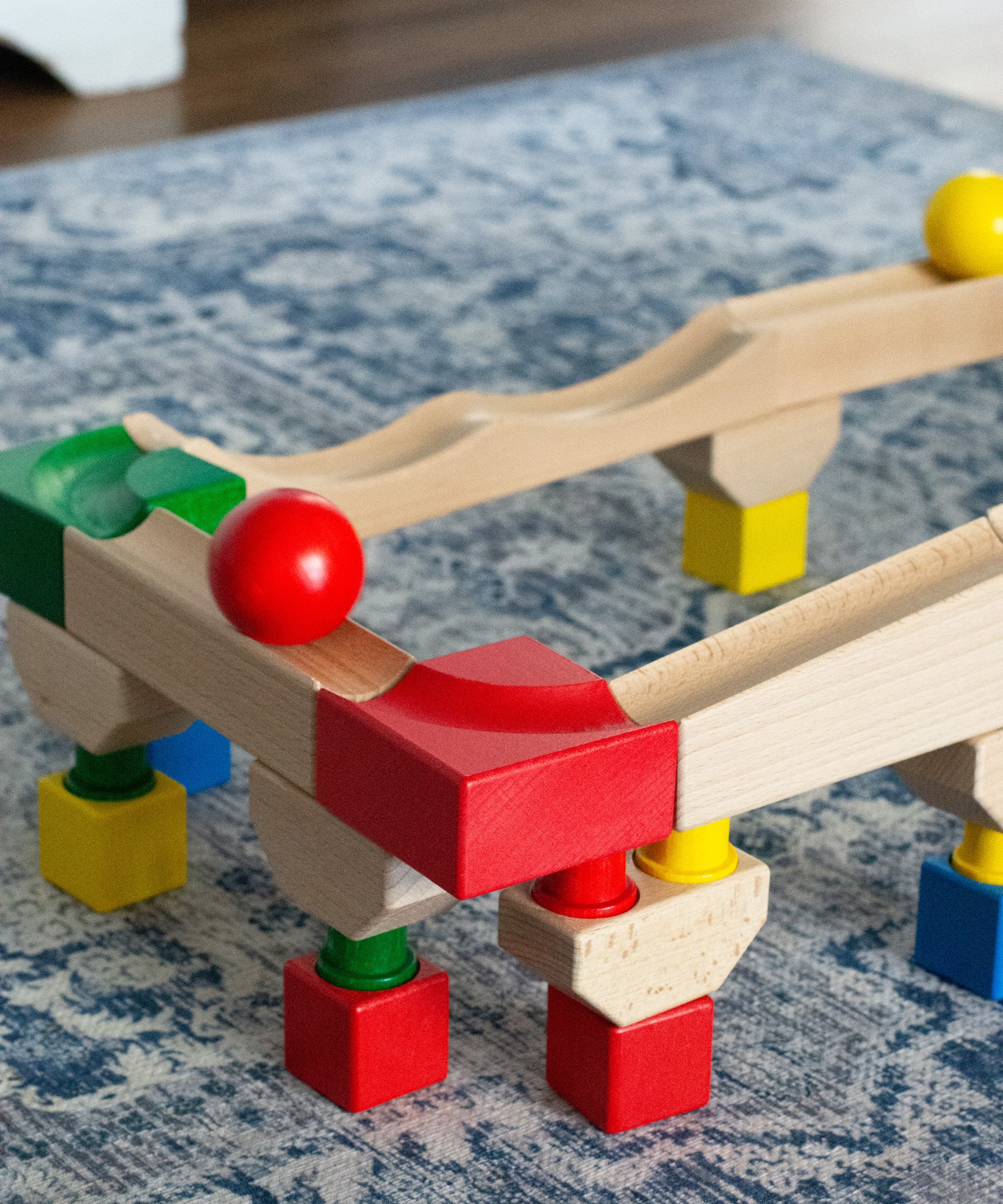 Nic Cubio wooden Ball Track Extension Set shown set up with a red  and yellow ball shown on motion on the track. Wooden balls are available to purchase separately. 