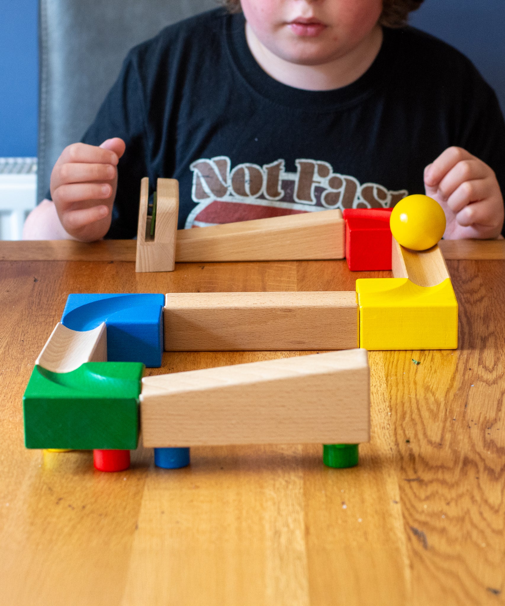 The Nic Cubio Wooden Marble Run Starter Set shown set up on a wooden table with the bell outlet add on added to the end. 
