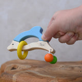 Nic dolphin wooden baby grasping toy in a child's hand.