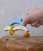Nic dolphin wooden baby grasping toy in a child's hand.