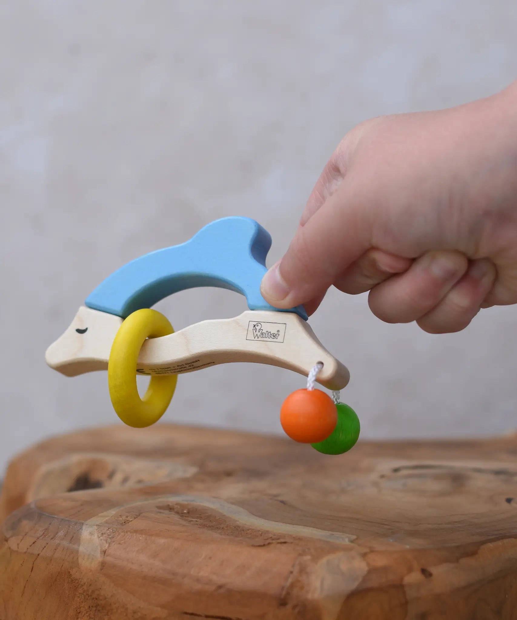 Nic dolphin wooden baby grasping toy in a child's hand.