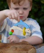 Nic dolphin wooden baby grasping toy in a child's hand.