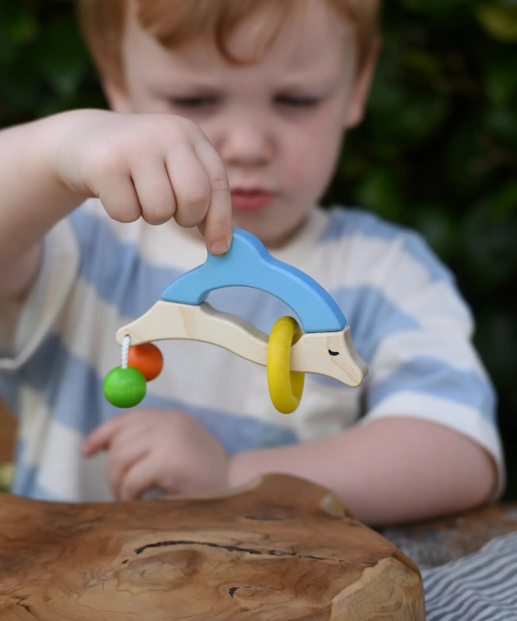 Nic dolphin wooden baby grasping toy in a child's hand.