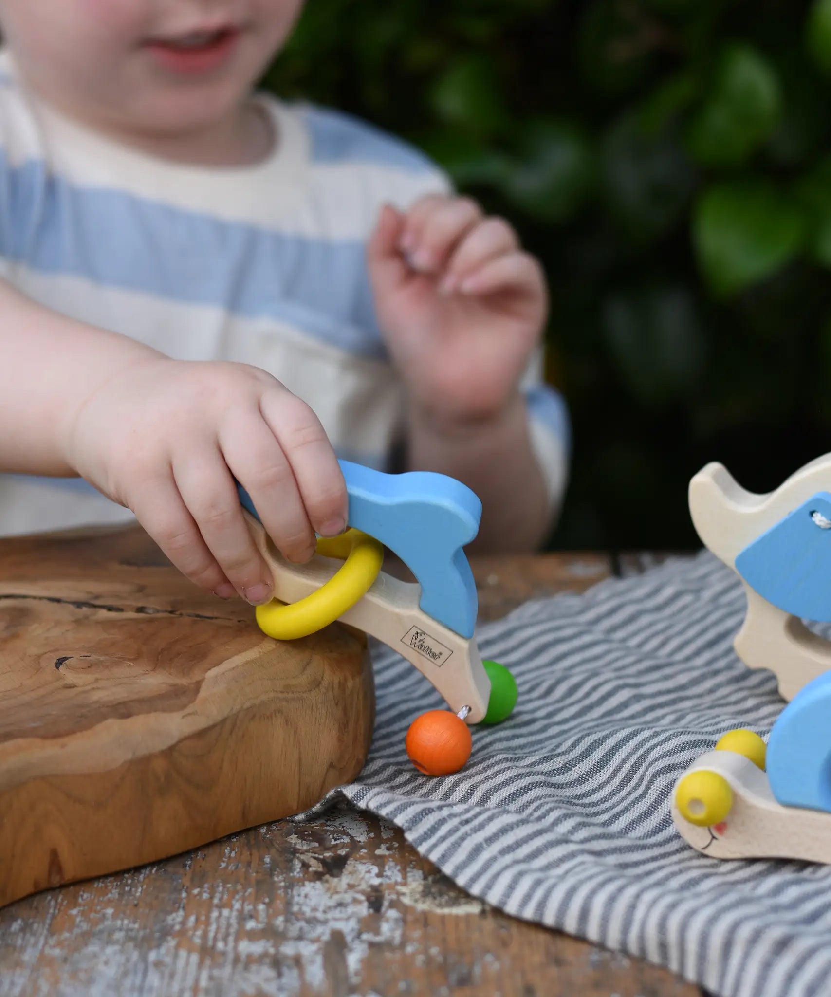 Child playing with the Nic dolphin wooden baby grasping toy.