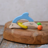 Nic dolphin wooden baby grasping toy placed on a wooden surface. 