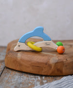 Nic dolphin wooden baby grasping toy placed on a wooden surface. 