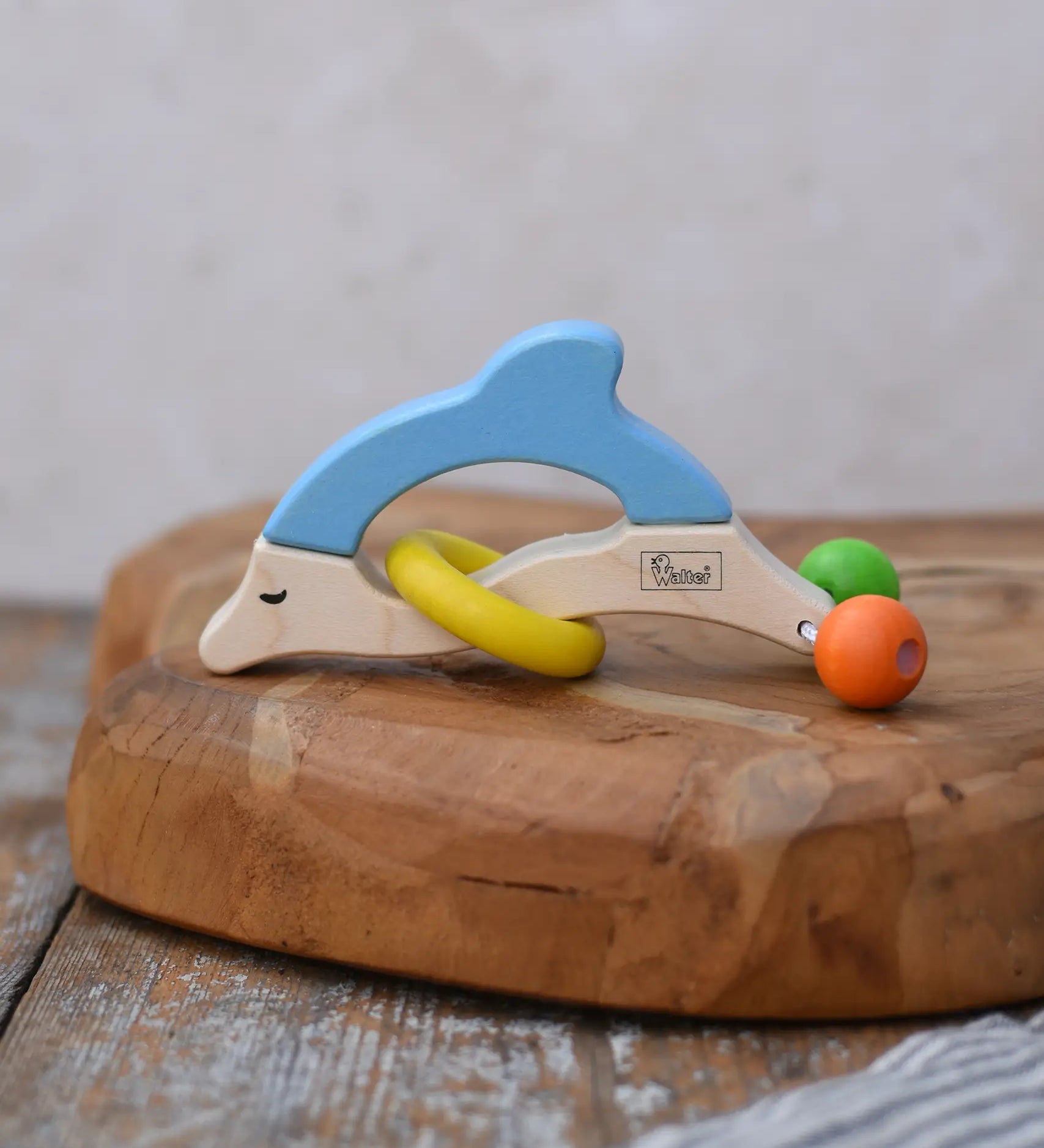 Nic dolphin wooden baby grasping toy placed on a wooden surface. 