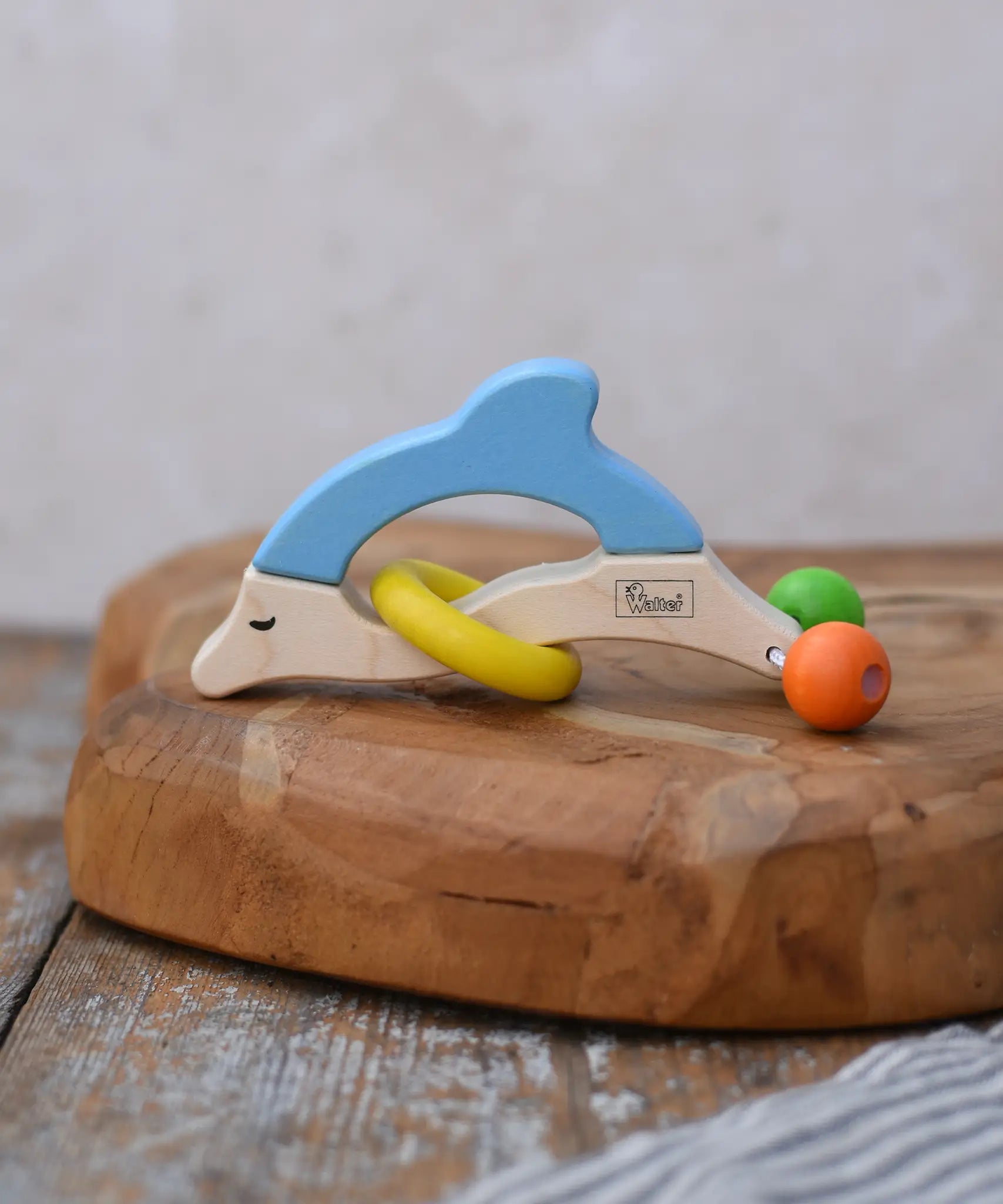 Nic dolphin wooden baby grasping toy placed on a wooden surface. 