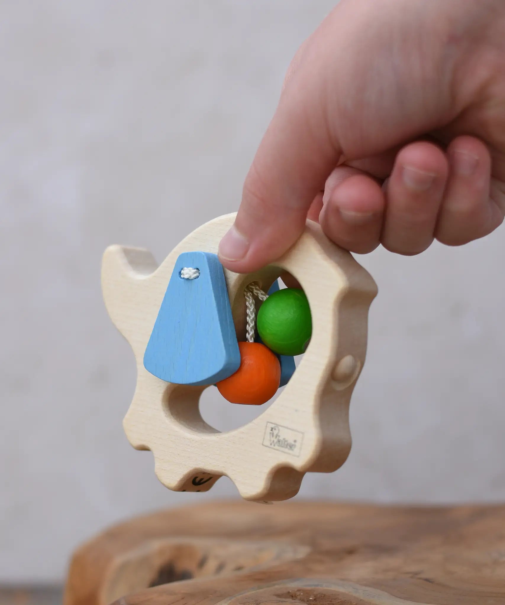 Back of the Nic elephant grasper wooden baby toy in a child's hand.