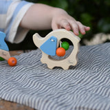 Child's hand reaching for the Nic elephant grasper wooden baby toy.