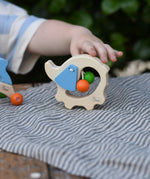 Child's hand reaching for the Nic elephant grasper wooden baby toy.