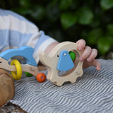 Child holding the back of the Nic elephant grasper wooden baby toy.