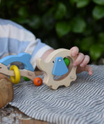 Child holding the back of the Nic elephant grasper wooden baby toy.