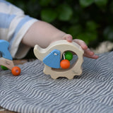 Child's hand holding the Nic elephant grasper wooden baby toy.