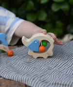 Child's hand holding the Nic elephant grasper wooden baby toy.