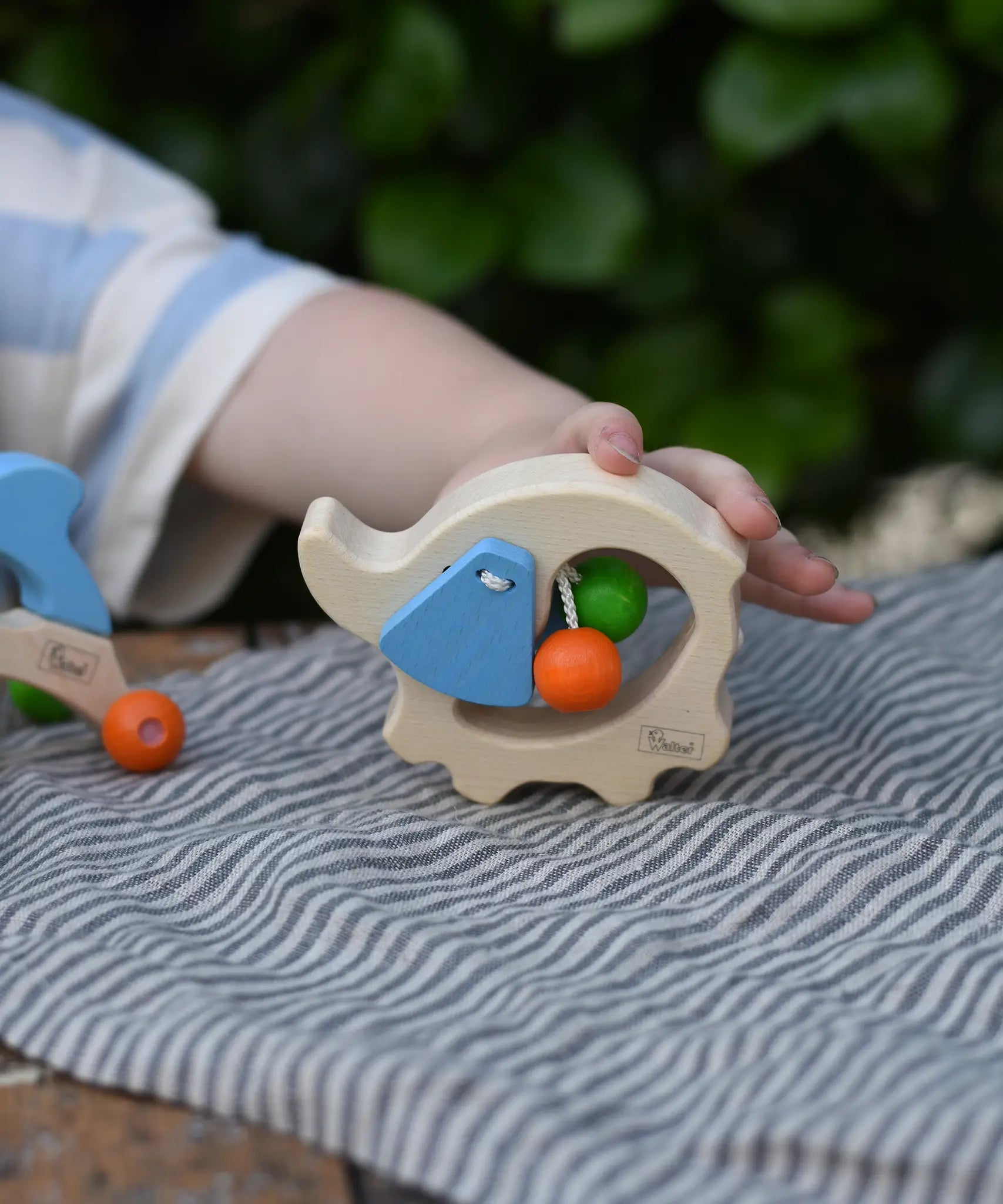 Child's hand holding the Nic elephant grasper wooden baby toy.