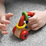A close up of a Nic First Wooden Car - Baby Push-Along Toy in a child's hand.