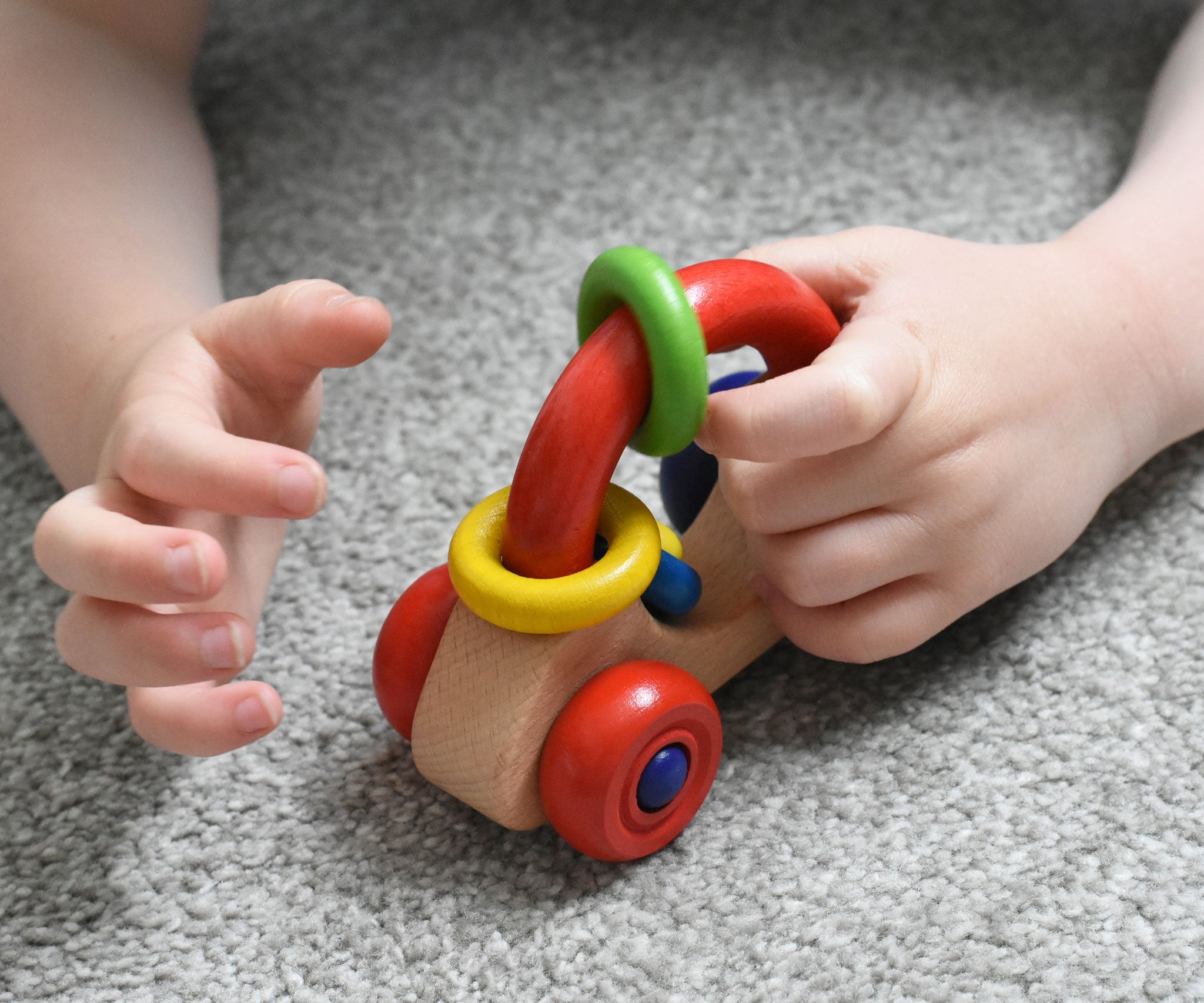 A close up of a Nic First Wooden Car - Baby Push-Along Toy in a child's hand.