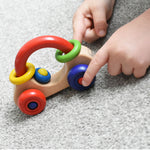 A close up of a child's hand playing with a Nic First Wooden Car - Baby Push-Along Toy.