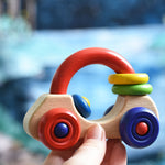 An adult's hand holding up a Nic First Wooden Car - Baby Push-Along Toy.