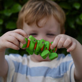 Child holding the Nic Willy the centipede green wooden baby toy up in front of their face.