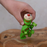 Nic Willy the centipede green wooden baby toy in a child's hand.
