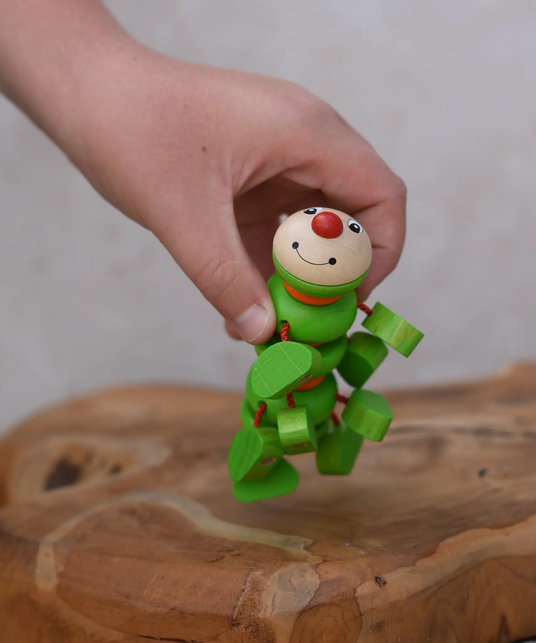 Nic Willy the centipede green wooden baby toy in a child's hand.