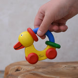 Child lifting up the Nic Toys wooden yellow grip duck baby toy.