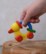Child lifting up the Nic Toys wooden yellow grip duck baby toy.