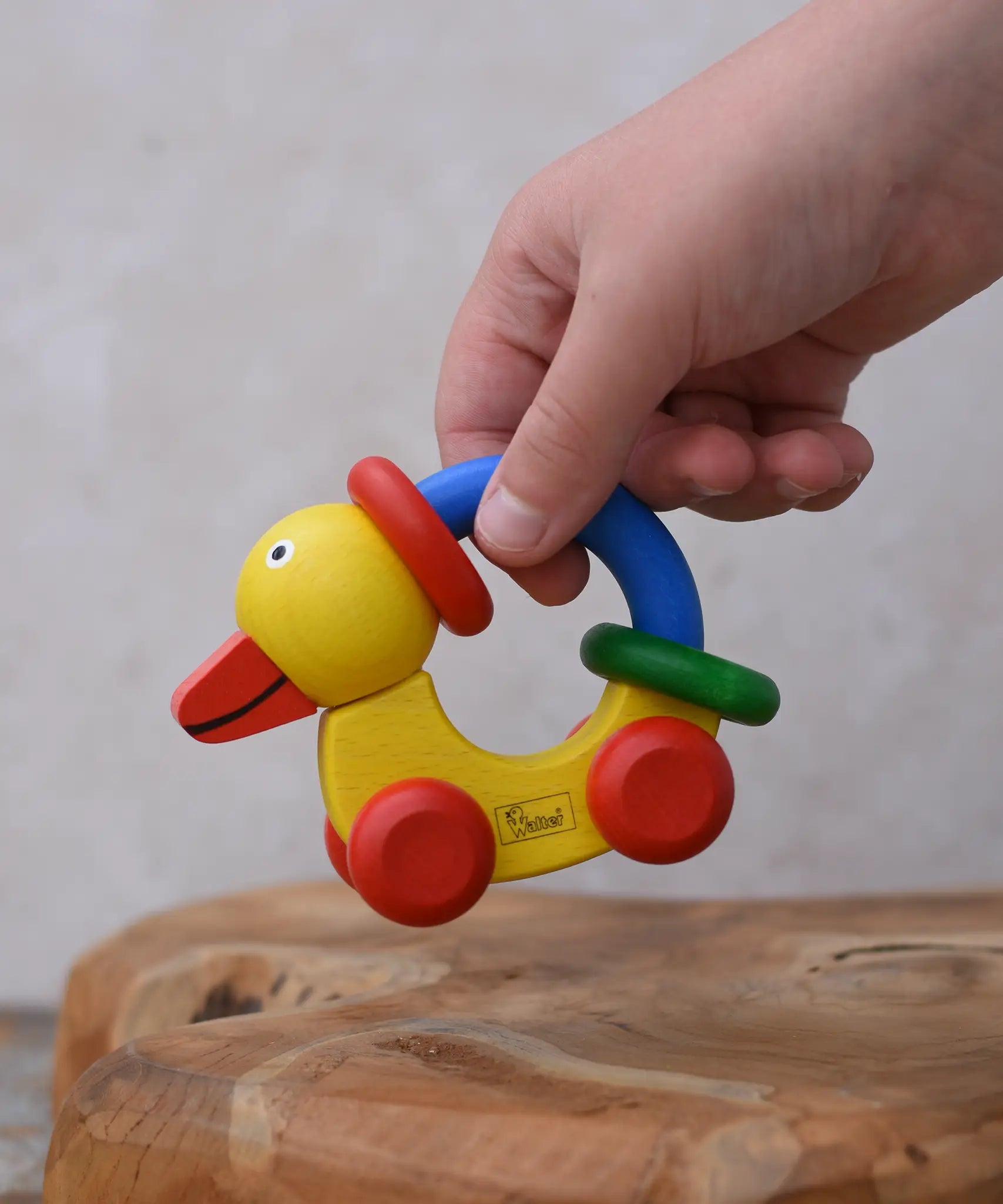 Child lifting up the Nic Toys wooden yellow grip duck baby toy.
