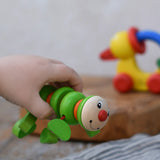 Nic Willy the centipede green wooden baby toy in a child's hand.