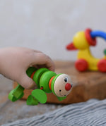 Nic Willy the centipede green wooden baby toy in a child's hand.