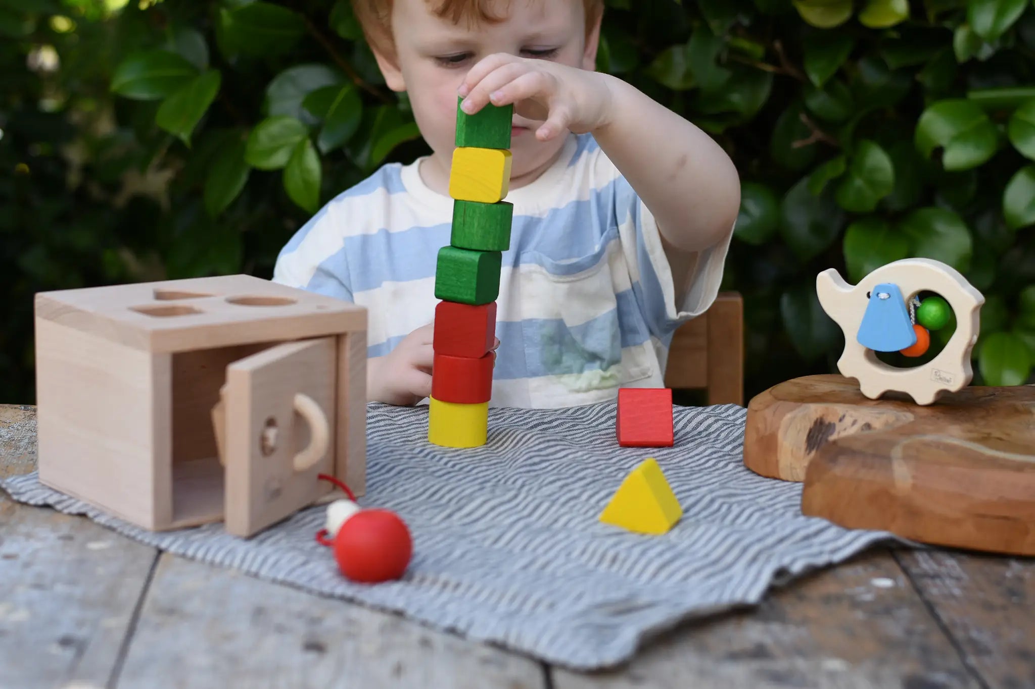 Child stacking the blocks from the Nic lock a bloc wooden shape sorter toy on top of each other. 