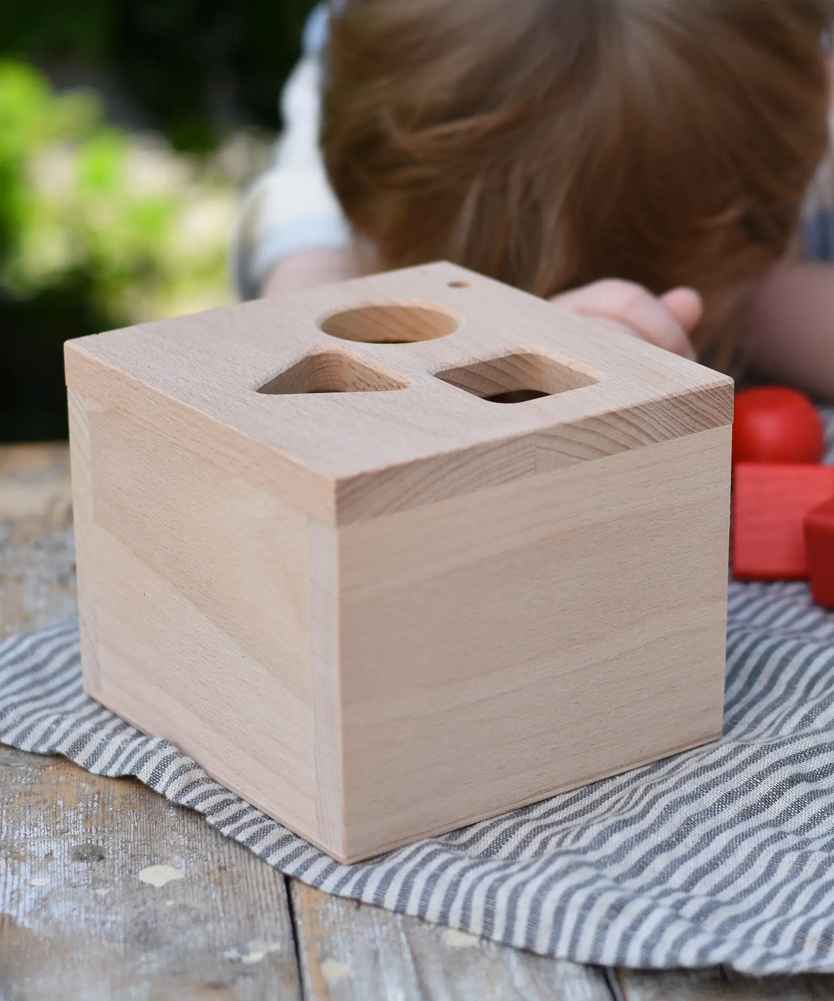 Top of the Nic lock a bloc wooden shape sorter toy box with three slots, triangle, square and circle.